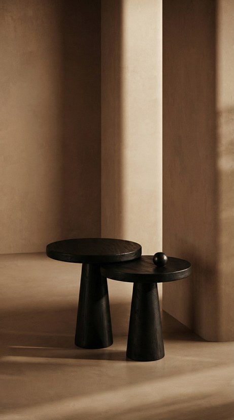 Mesa auxiliar escultorica en madera negra sobre fondo de muro beige